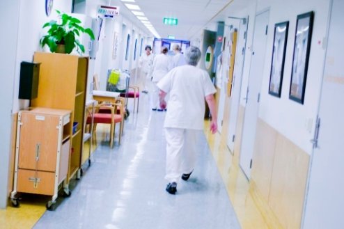 En pleier i hvite klær haster ned en korridor på et sykehus. Foto: Delta