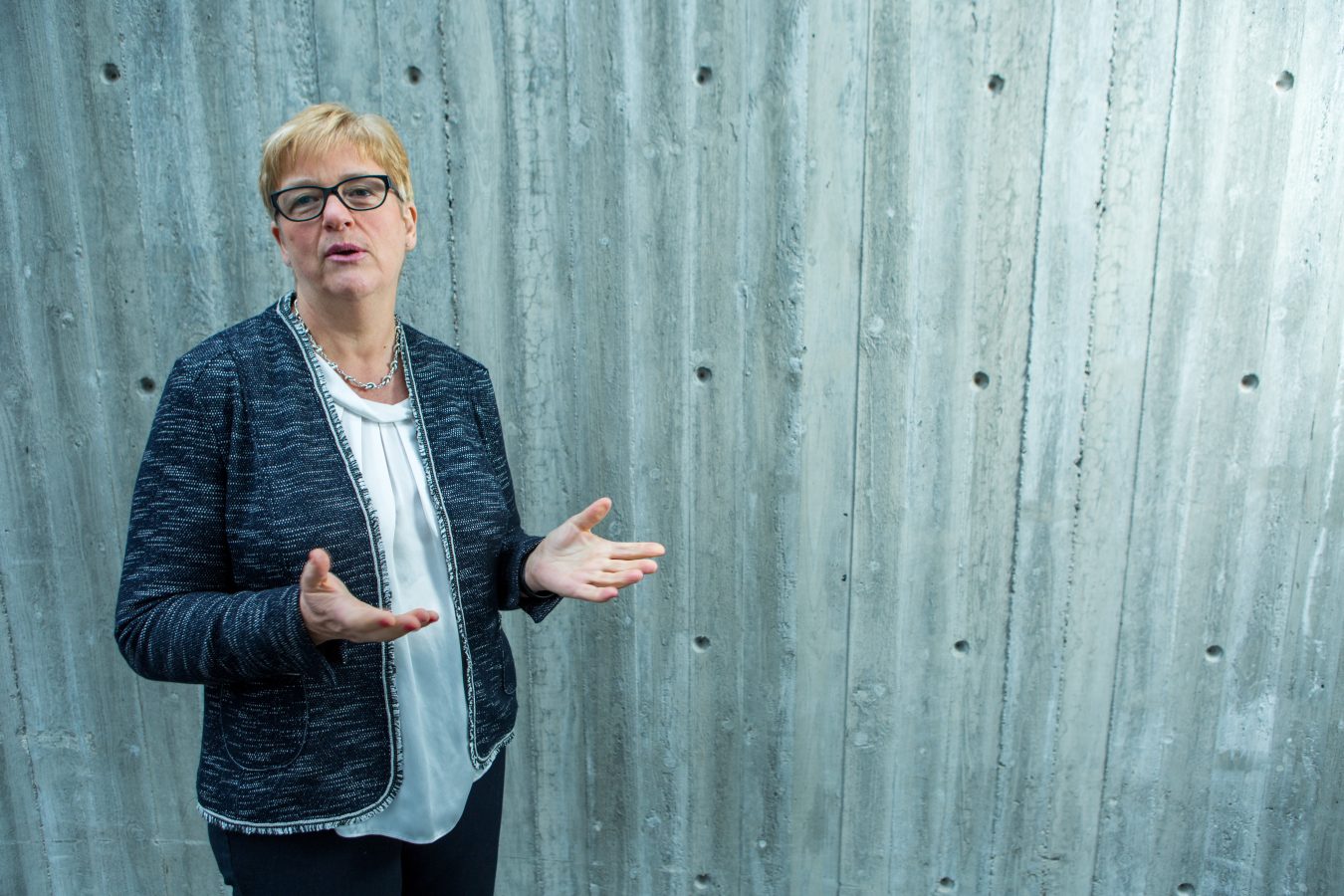 YS-leder Jorunn Berland står foran en grå vegg. Hun snakker, og gestikulerer med åpne hender.