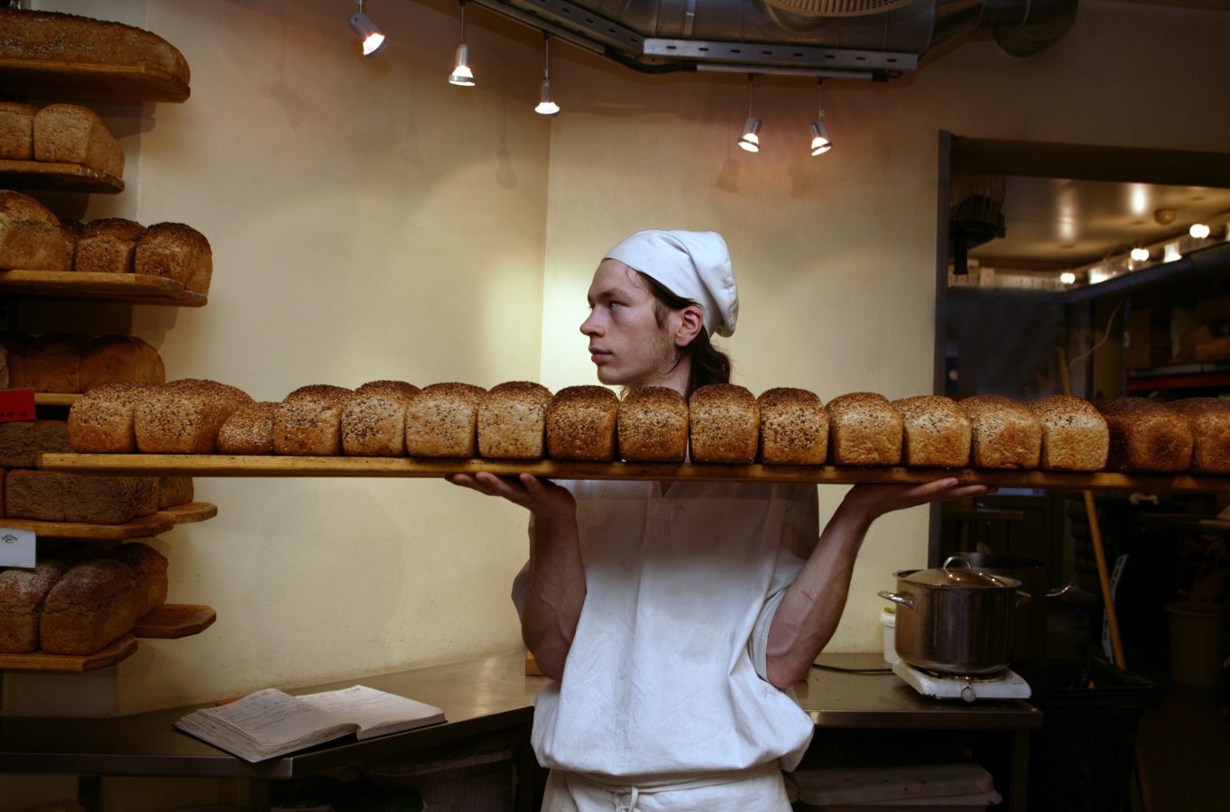 Ung mann tar et brett brød ut av ovnen. Foto: Berit Roald/ Scanpix ven.