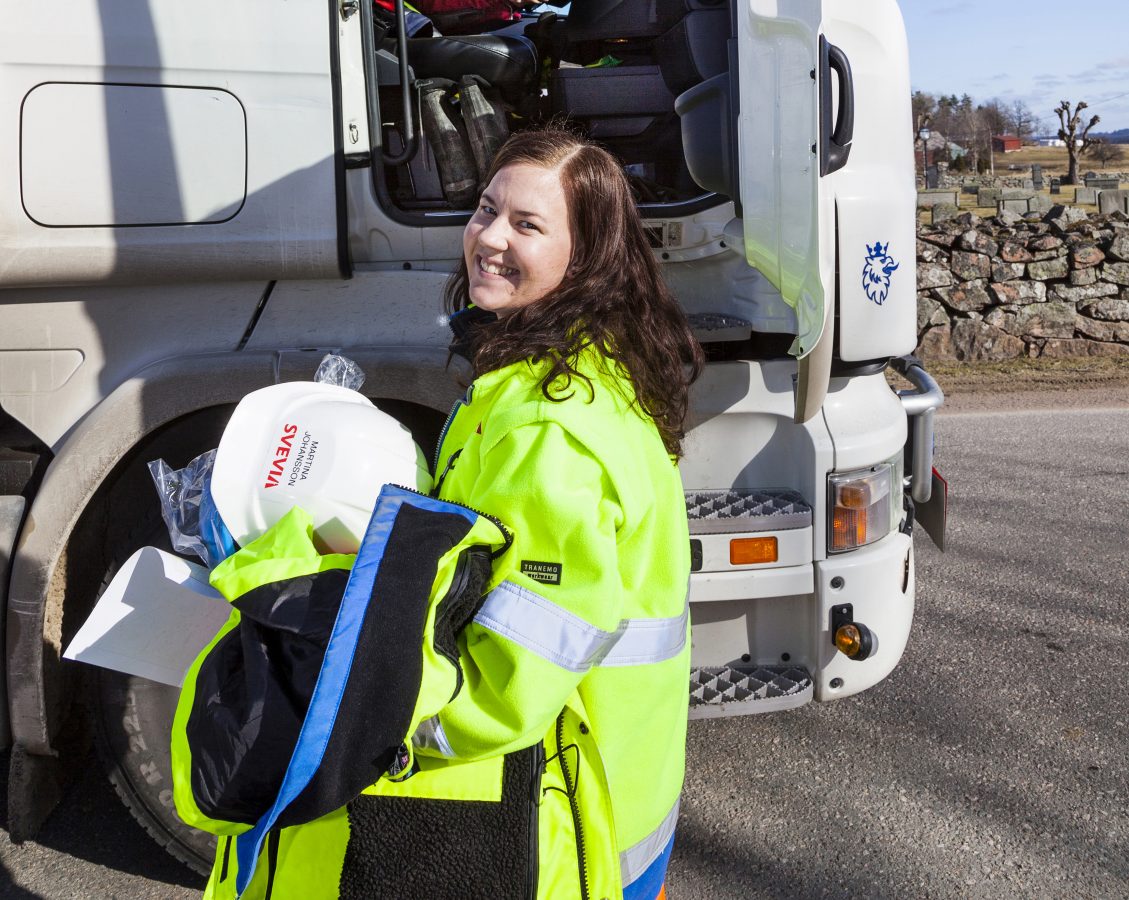 Ung jente i gult arbeidstøy står utenfor en lastebil.