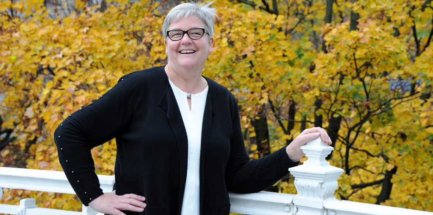 avtroppende YS-leder Jorunn Berland mot høstgule balder, mens hun holder på et hvitt rekkverk ute.