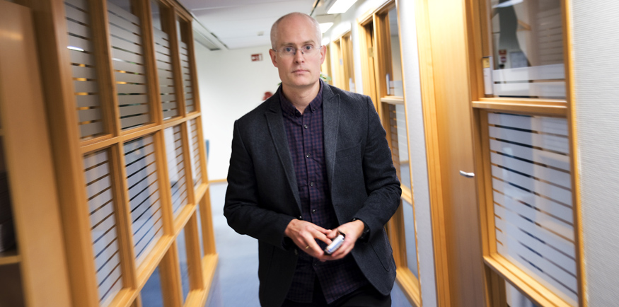 Forsker Anders Underthun står i en korridor med en telefon i hånda. 