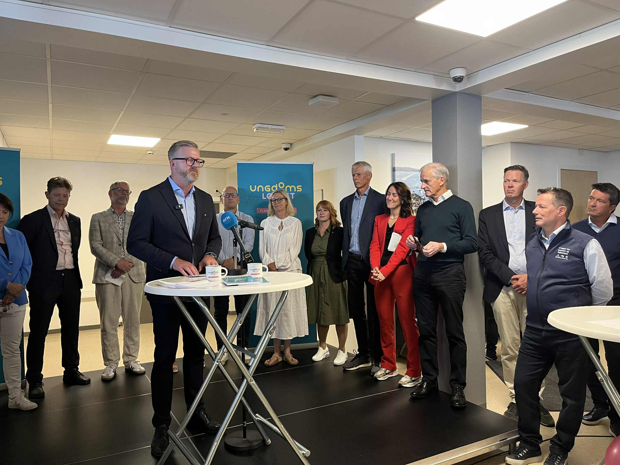 YS-leder Hans-Erik Skjæggerud står i midten av bildet, ved et hvitt bord. Han signerer en avtale kalt Ungdomsløftet sammen med de andre partene i arbeidslivet, statsminister Støre og noen statsråder.